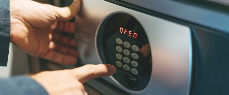 Adult man in blue jacket uses safe in the hotel room