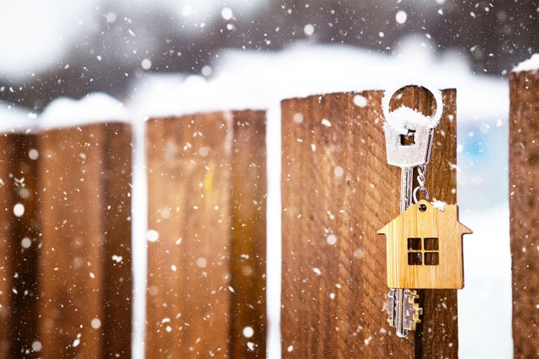 Key to the house on a wooden fence in winter in the snow. A gift