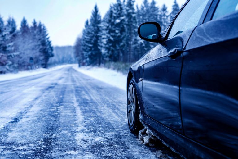 black-car-iced-road-surrounded-by-trees-covered-with-snow